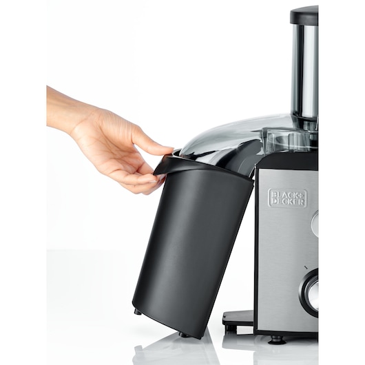 BLACK+DECKER JE800 juicer side view with hand removing black pulp container, stainless steel body, white background.