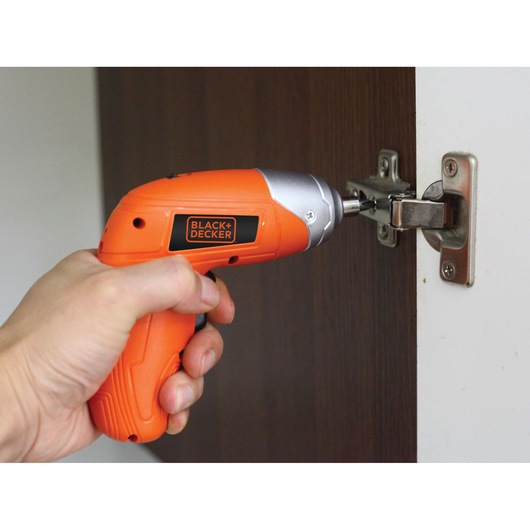 BLACK+DECKER KC3610 cordless orange screwdriver used to fasten cabinet hinge.