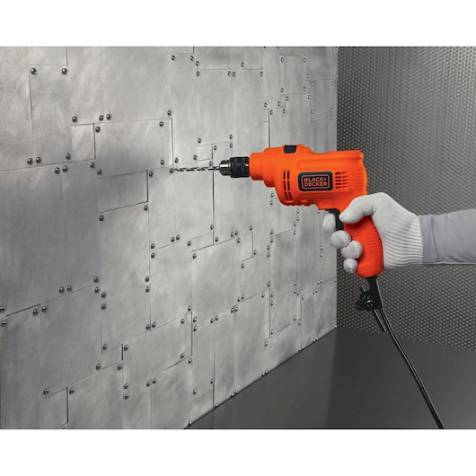 BLACKDECKER KR5010 orange corded drill held against a metal wall, side angle.