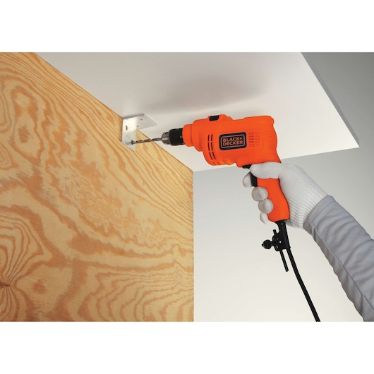 BLACKDECKER KR5010 orange corded drill used on a metal bracket, side angle, product in hand.