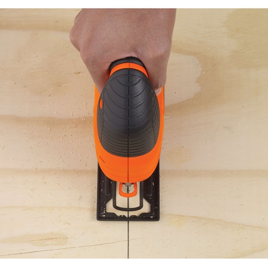Top view of BLACKDECKER KS701EK jigsaw cutting along a marked line on light wood surface.