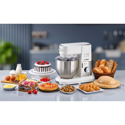 BLACKDECKER MKM100 stand mixer with stainless steel bowl on kitchen counter, surrounded by baked goods and ingredients, front angle.