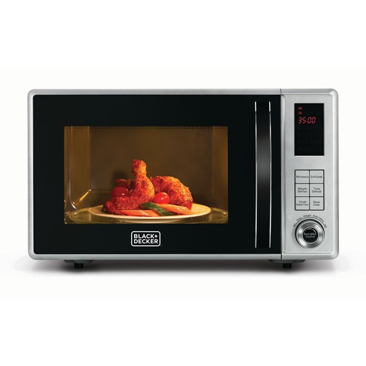 A BLACK+DECKER microwave oven with a digital control panel, displaying 35:00 on the timer. Inside the microwave, a plate with cooked chicken drumsticks and vegetables is visible through the door.