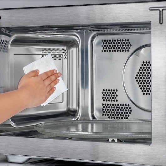 BLACKDECKER MZAF2910 microwave interior being cleaned with a paper towel, close-up photography.