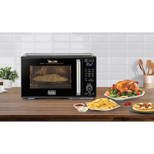 BLACK+DECKER MZAF2910 countertop microwave oven with digital display, shown in kitchen with food plates, front angle.