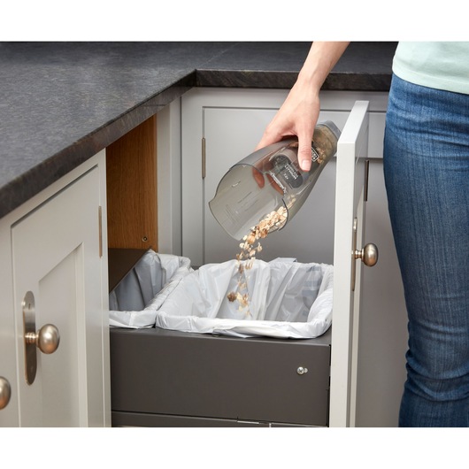 Photo of BLACKDECKER NVC215W handheld vacuum being emptied into a kitchen trash bin.