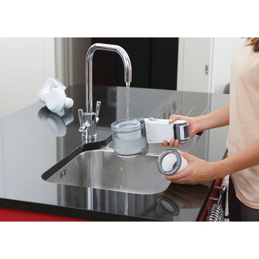BLACKDECKER PV1820L handheld vacuum being cleaned at a kitchen sink, filter and dust container visible.
