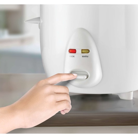 BLACKDECKER RC1050 rice cooker side view with hand pressing control switch and cook, warm indicator lights.