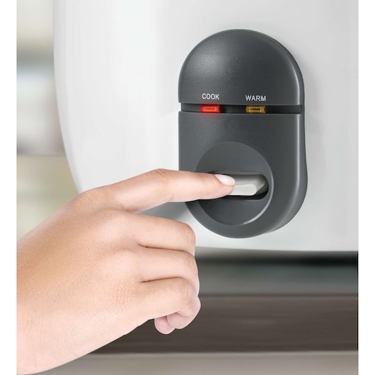 BLACKDECKER RC1860 rice cooker control panel with cook and warm lights, close-up with hand pressing button.