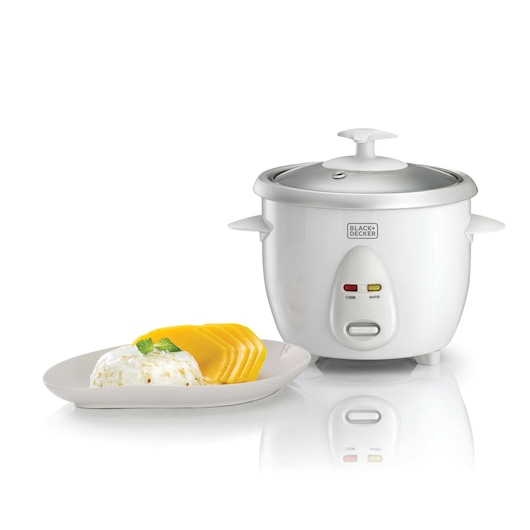 A BLACK+DECKER rice cooker with a white exterior and a glass lid is shown next to a plate of food that includes rice pudding and sliced mango.