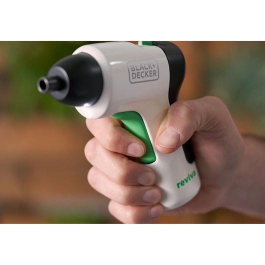 Close-up photo of BLACK+DECKER REVSD4C cordless screwdriver with white body, green detail, and black tip held in hand.
