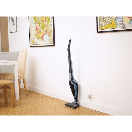 BLACKDECKER SVA420B stick vacuum cleaner charging in a modern room with wooden floor.