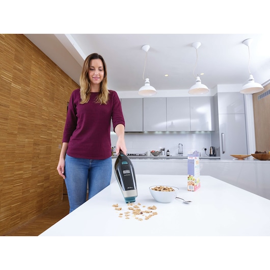 BLACKDECKER SVA420B handheld vacuum cleaning cereal from a kitchen table, photography front angle.