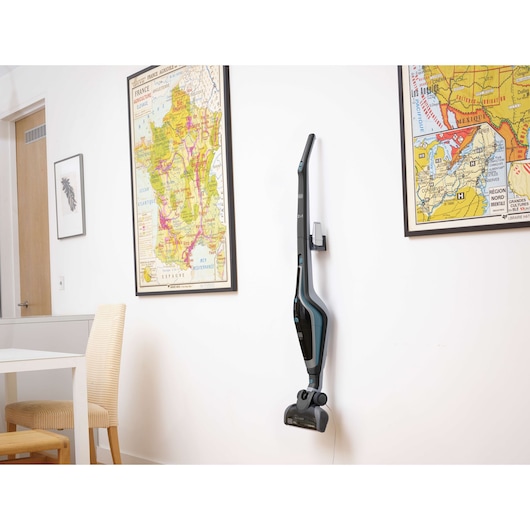Photo of BLACKDECKER SVA420B cordless stick vacuum mounted on wall in a modern room with framed maps.