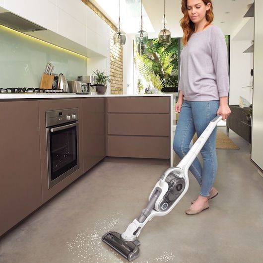 BLACKDECKER SVFV3250L cordless stick vacuum in white and grey cleaning kitchen floor, home setting.
