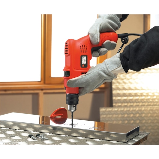Photo of BLACKDECKER TM500 drill in use on metal surface, held by gloved hands, product category: Photography.