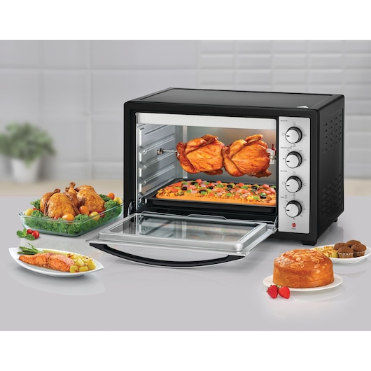 BLACKDECKER TRO50RDG countertop oven with rotisserie, knobs visible, shown with pizza and chicken inside, side angle.