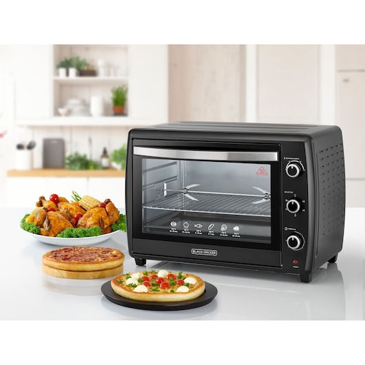 BLACKDECKER TRO70RDG countertop oven with three control knobs, displayed with roast chicken and pizzas, front angle.