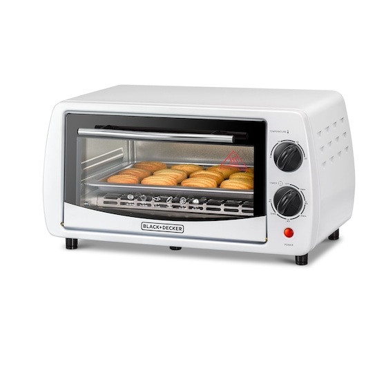 A white BLACK+DECKER toaster oven with cookies baking inside, featuring two control dials for temperature and timer settings on the right front side.