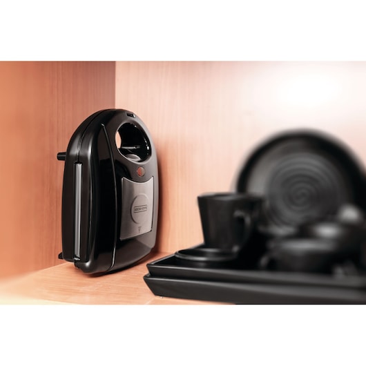 BLACKDECKER TS2120 sandwich maker in black and silver, upright on a wooden kitchen shelf next to black tableware.