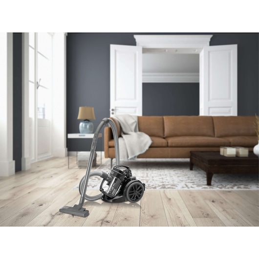 BLACKDECKER VM1480 canister vacuum cleaner on wood floor, living room setting, brown sofa in background.