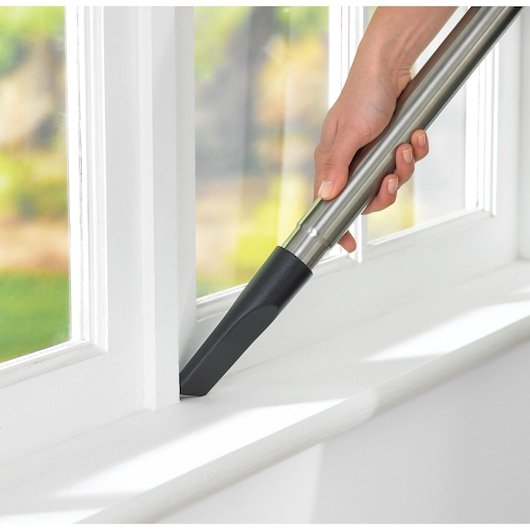 BLACKDECKER VM2825 vacuum nozzle cleaning window sill, close-up photography.