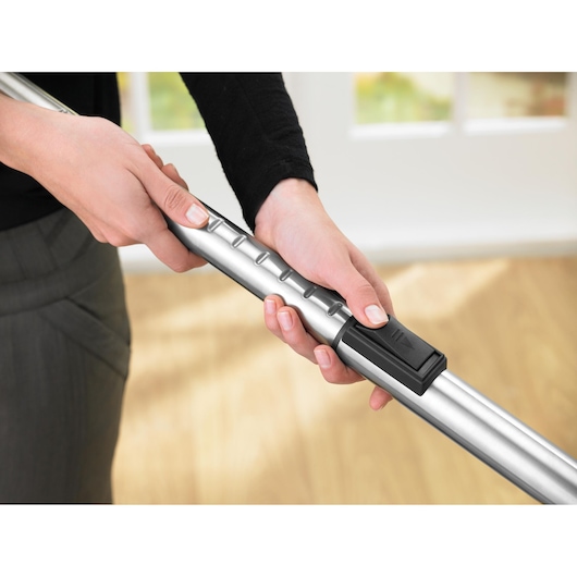 BLACKDECKER VM2825 adjustable silver vacuum tube held by hands in close-up view, indoors.