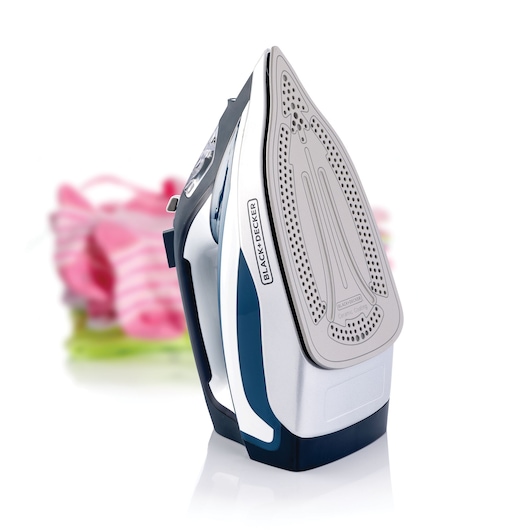 Photo of BLACK+DECKER X2150 steam iron upright on white background, ceramic soleplate visible, blurred clothes behind.