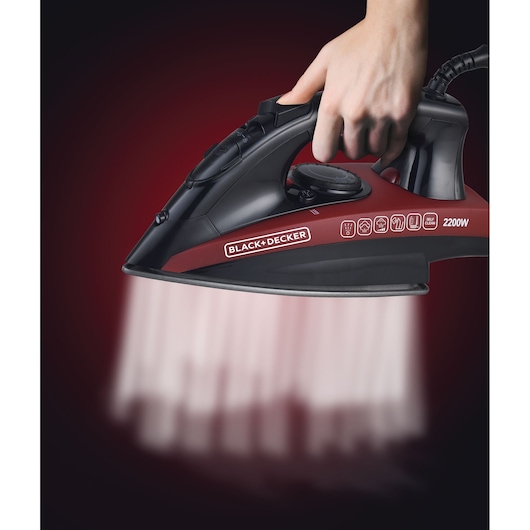 Photo of BLACK+DECKER X2200 steam iron in use, black and red body, 2200W, releasing steam downward.