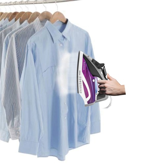 A hand holds a BLACK+DECKER steam iron, emitting steam onto a light blue dress shirt hanging on a rack with other shirts.